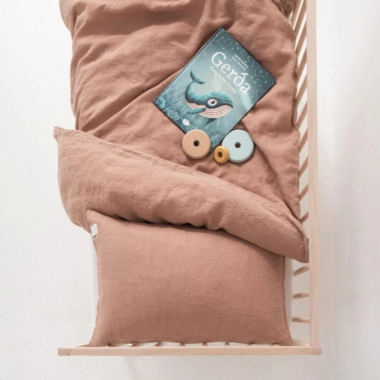 Pink bedding set with a children's book titled 'Gerda' on a white background