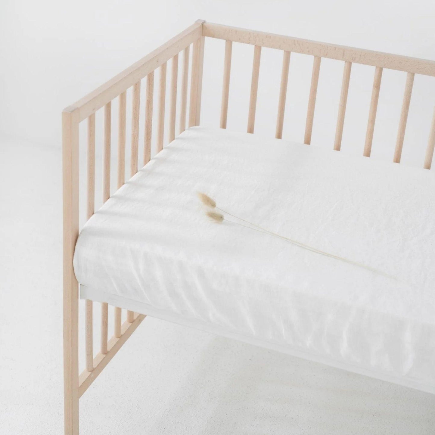 Wooden crib with white mattress against a white background
