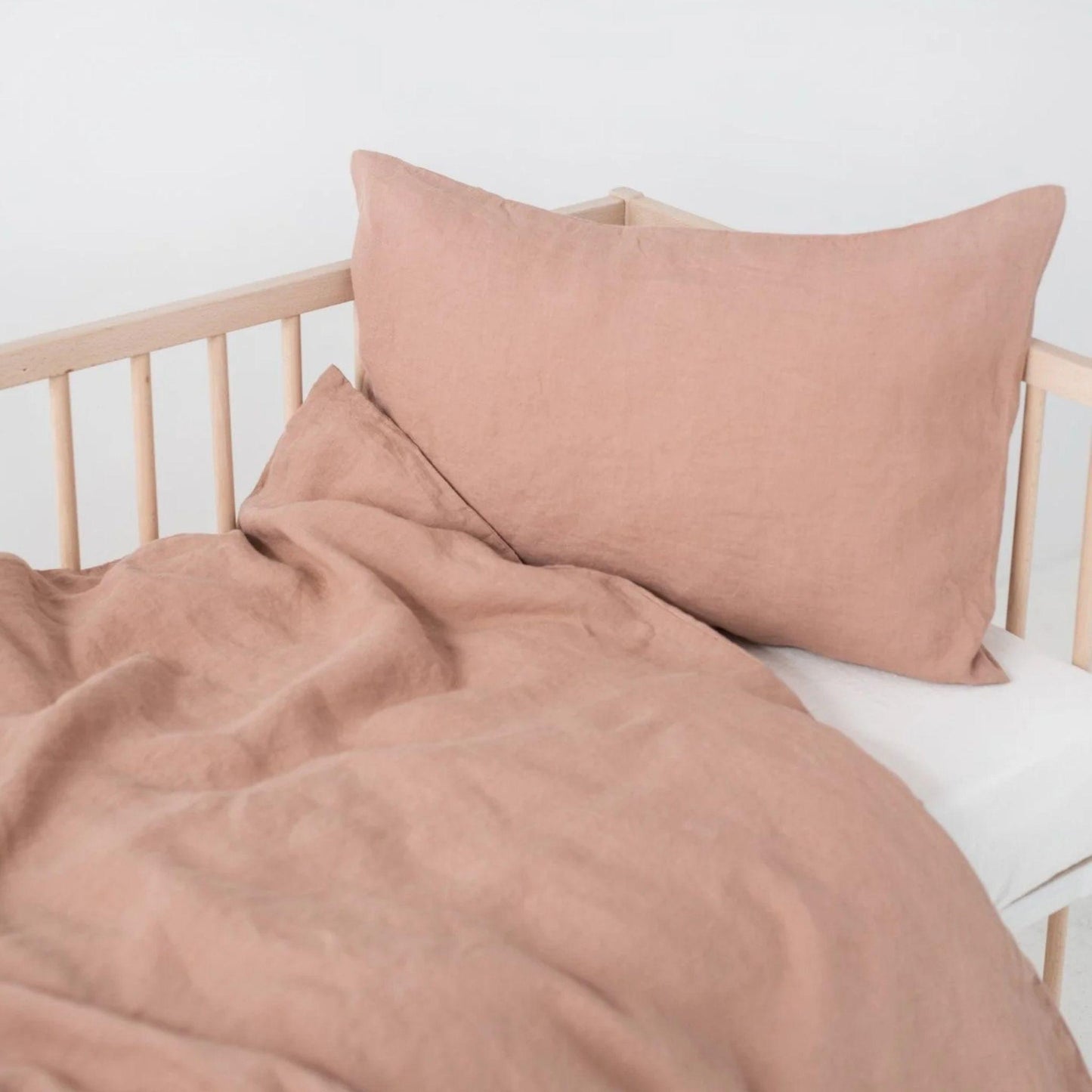 Bed with pink bedding and pillows against a white wall