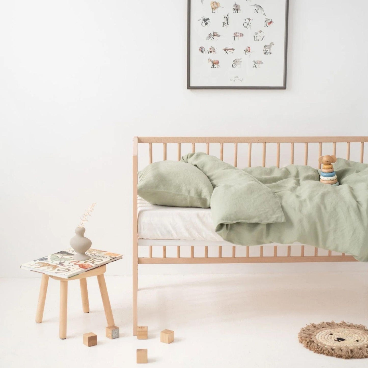 Children's room with a wooden bed, green bedding, and toys on a white floor.
