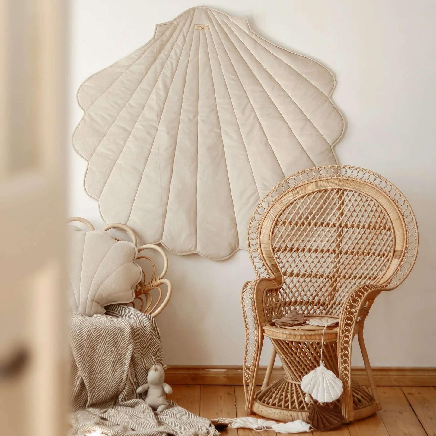 Wicker chair and shell-shaped wall art in a room with wooden floor.