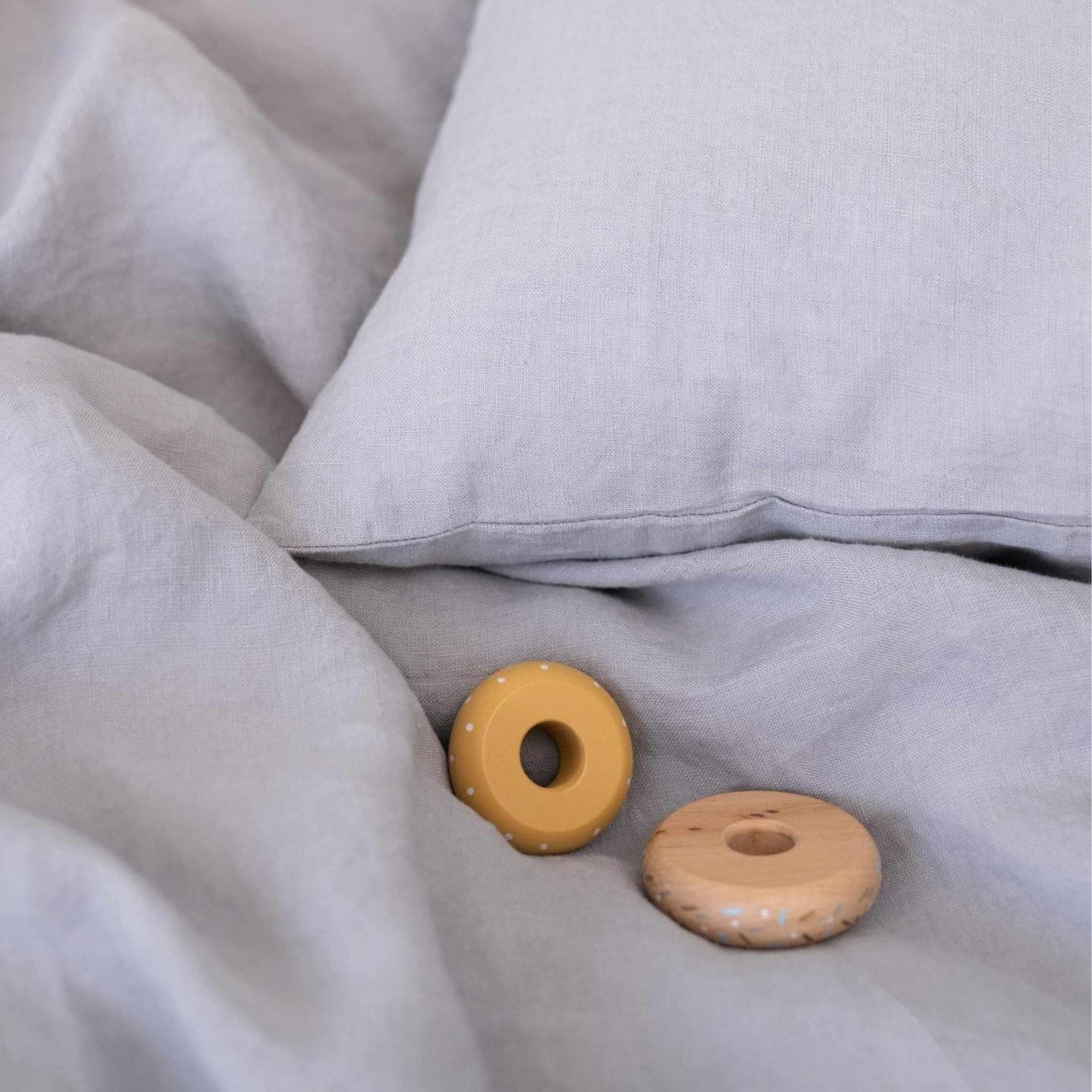 Two wooden donut-shaped toys on a soft gray fabric surface