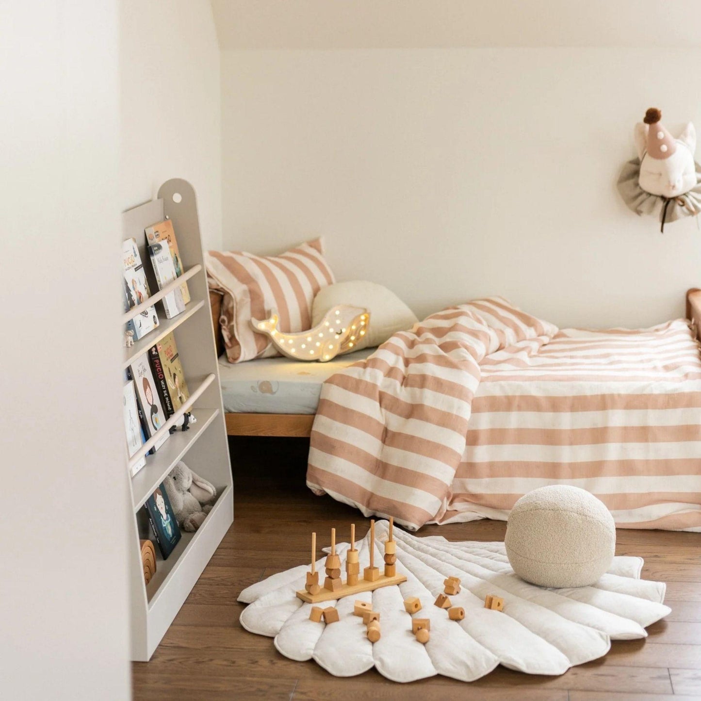 Children's bedroom with striped bedding, toys, and a bookshelf.