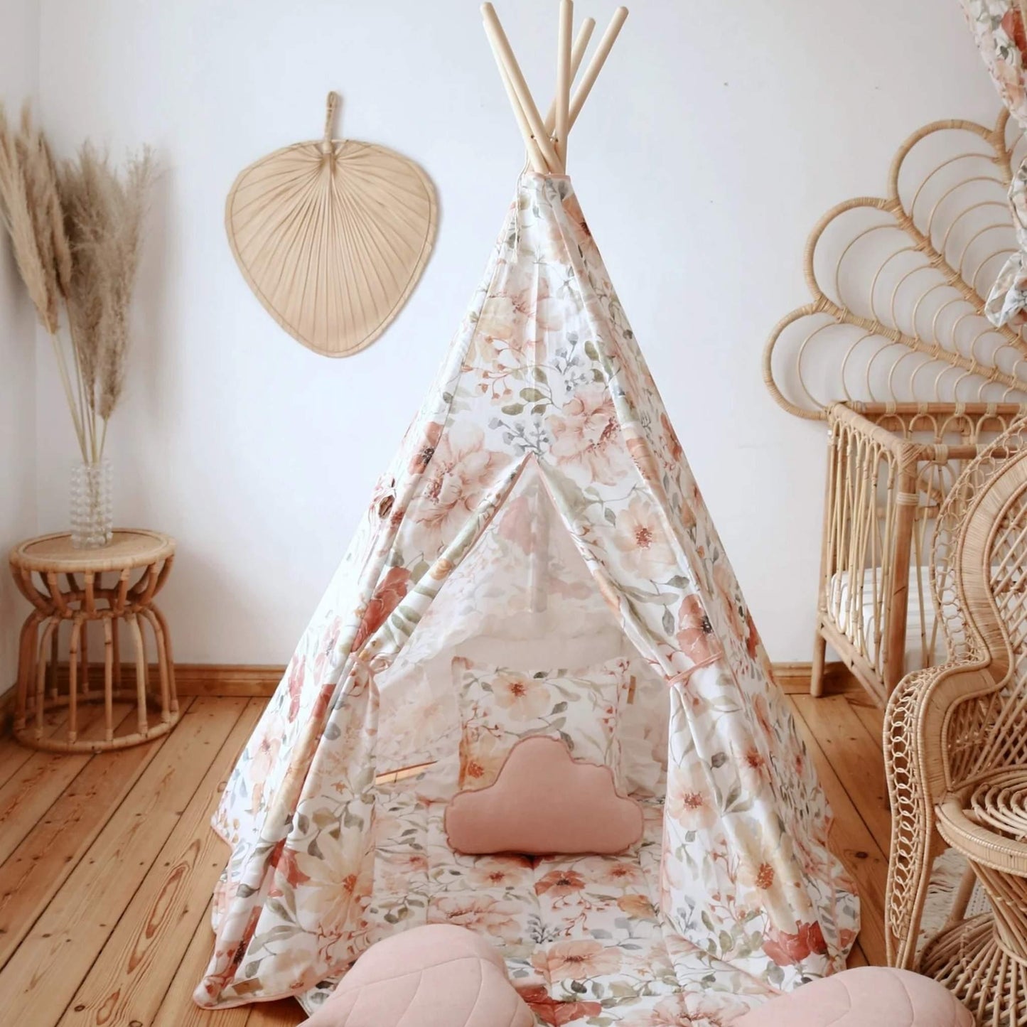 Floral-patterned teepee in a child's room with wicker furniture and decor.