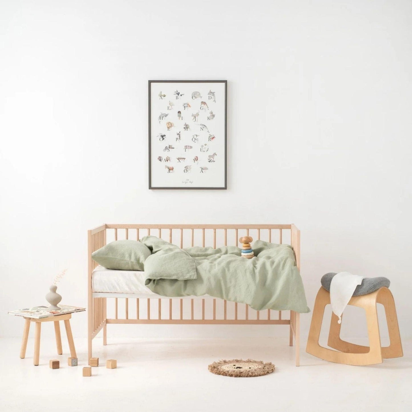 Children's room with a wooden crib, green bedding, and a framed picture on the wall.