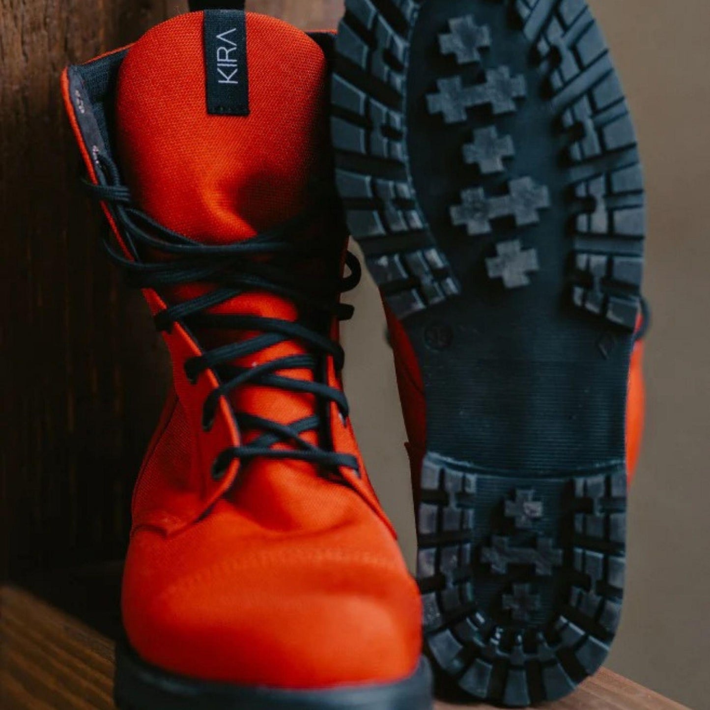 Orange hiking boots with black soles on a wooden surface