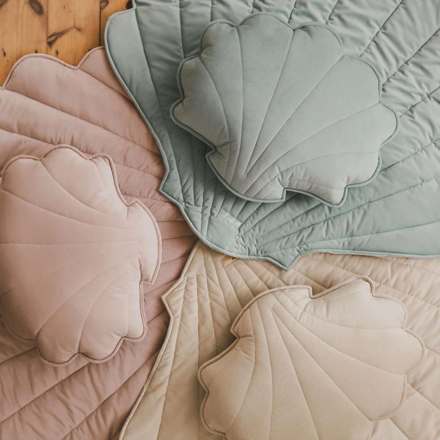 Shell-shaped cushions in pastel colors on a wooden surface