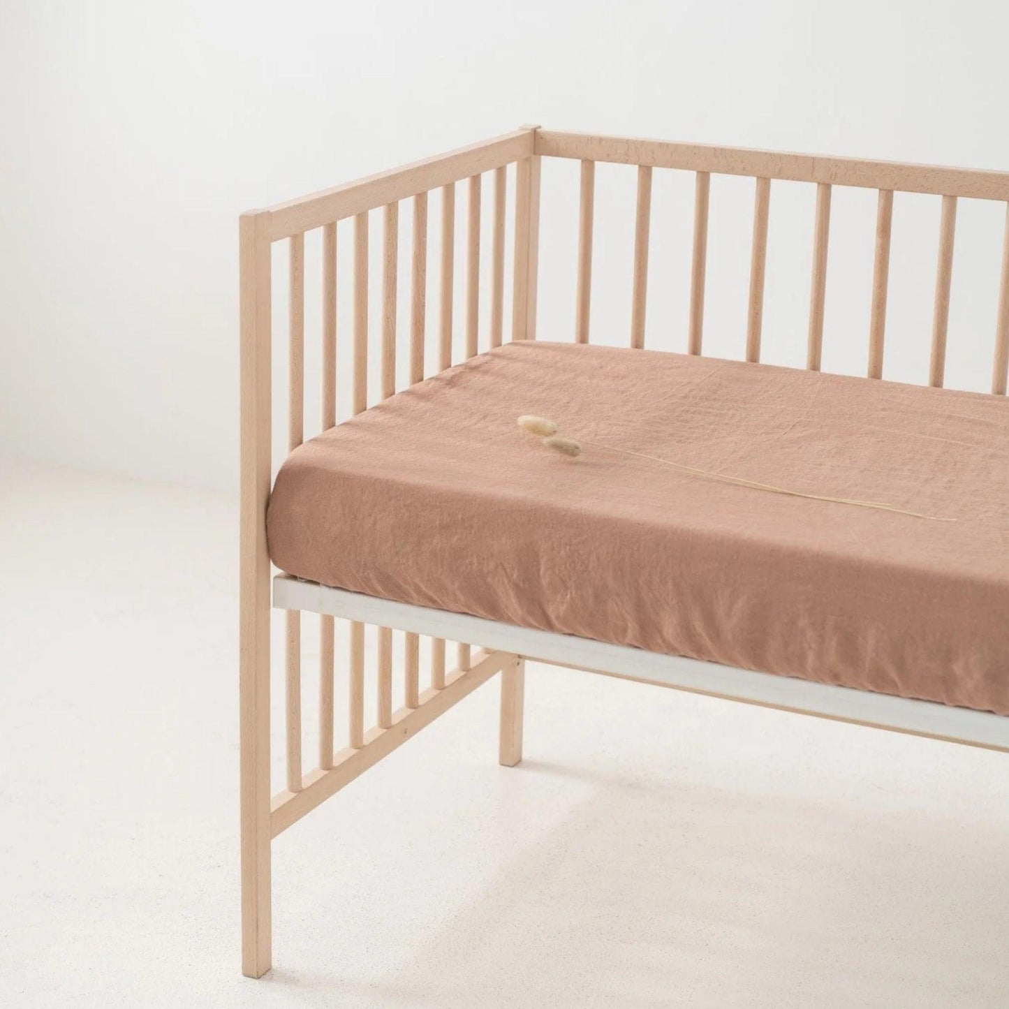 Wooden crib with a beige mattress on a white background