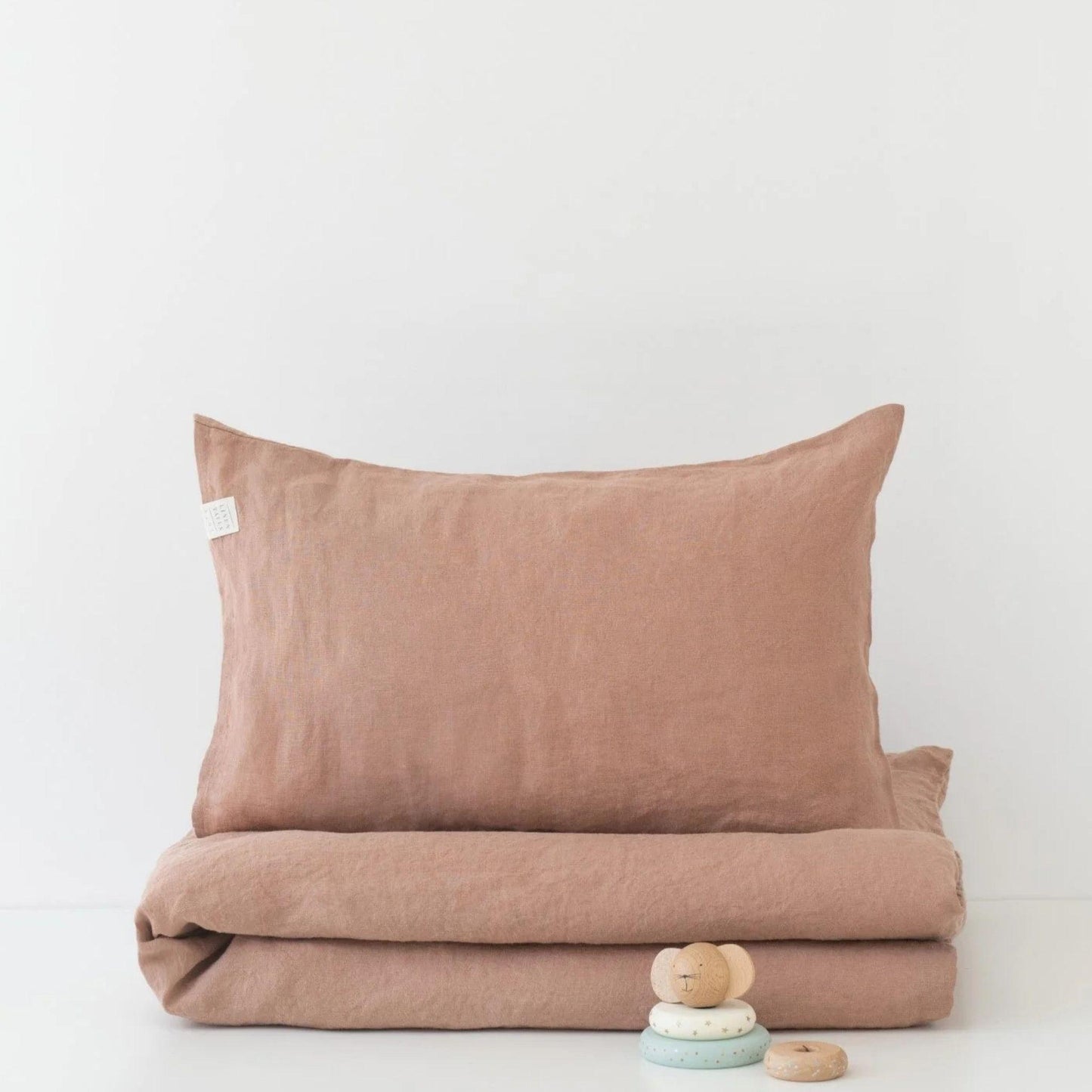Brown bedding set with folded duvet and pillow on a white background