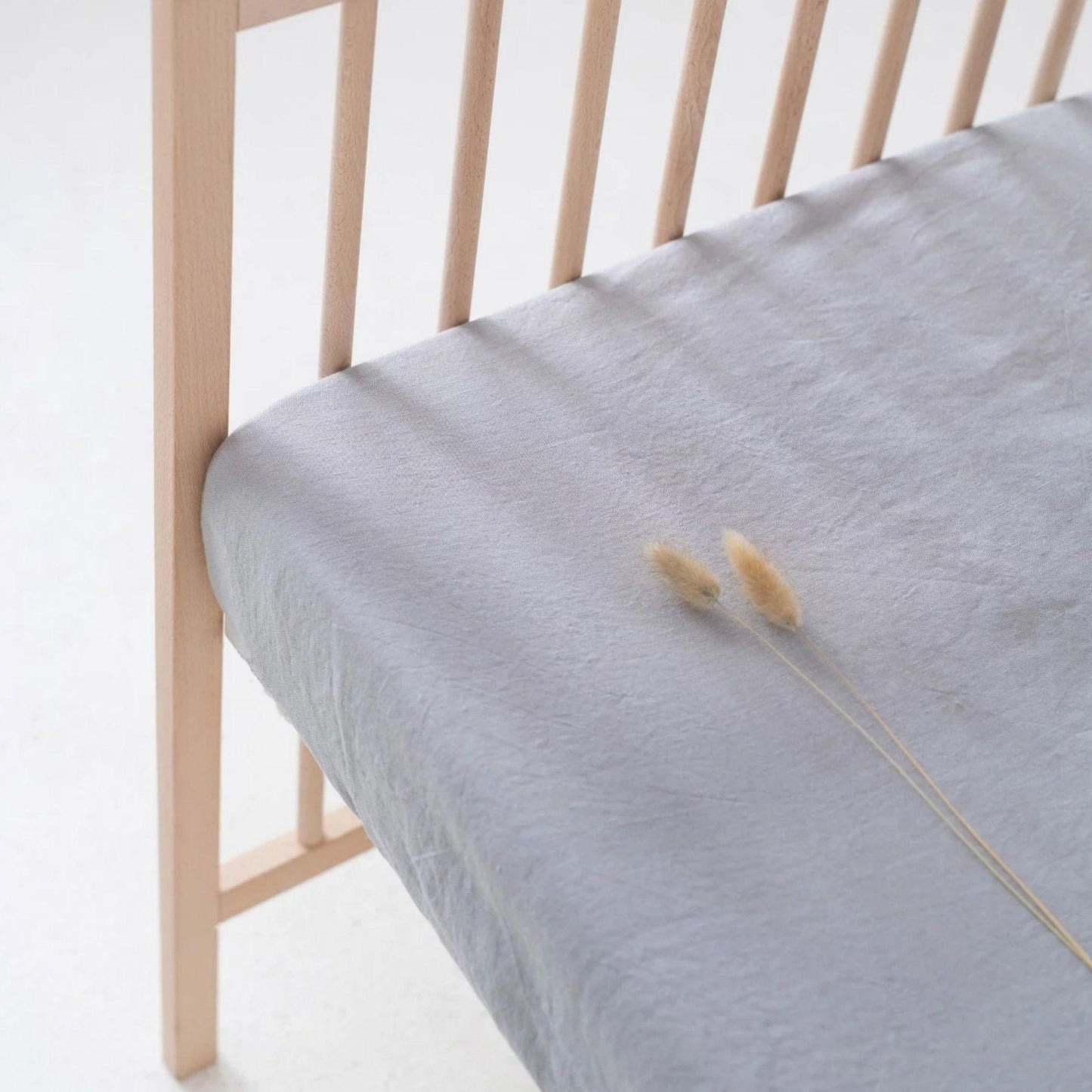 Light blue mattress cover on a wooden bed frame with a white background