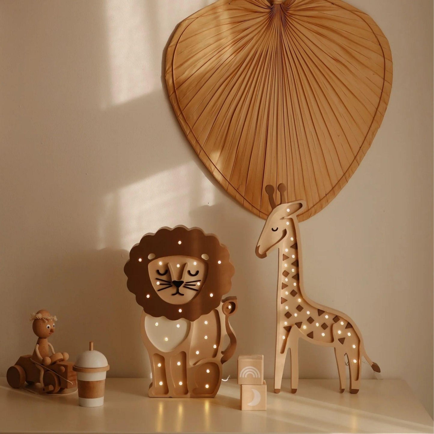 Decorative lion and giraffe lights with a child's toy and blocks on a neutral background