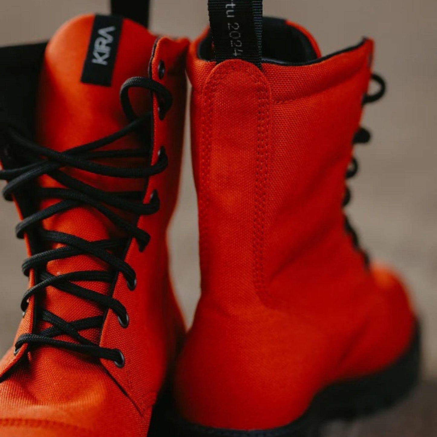 Red boots with black laces and visible branding on a neutral background