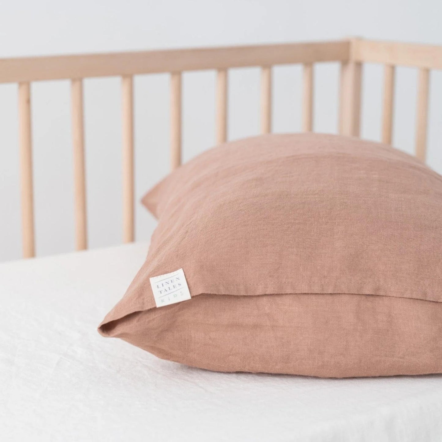 Brown pillow with a label on a bed with a wooden headboard.