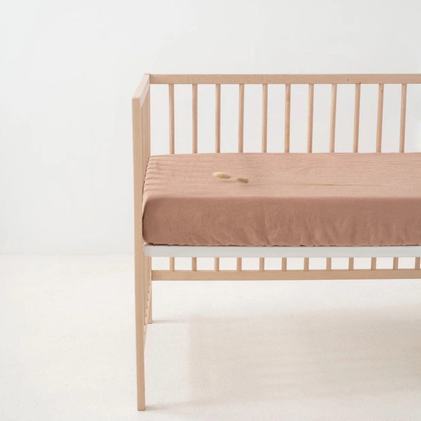 Wooden crib with a beige mattress on a white background