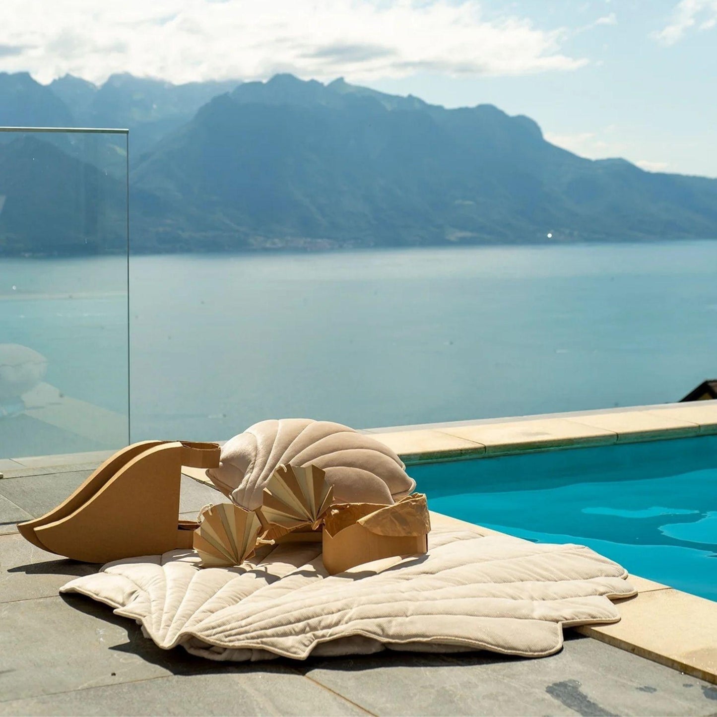 Beige outdoor furniture with a shell design by a pool and mountain view