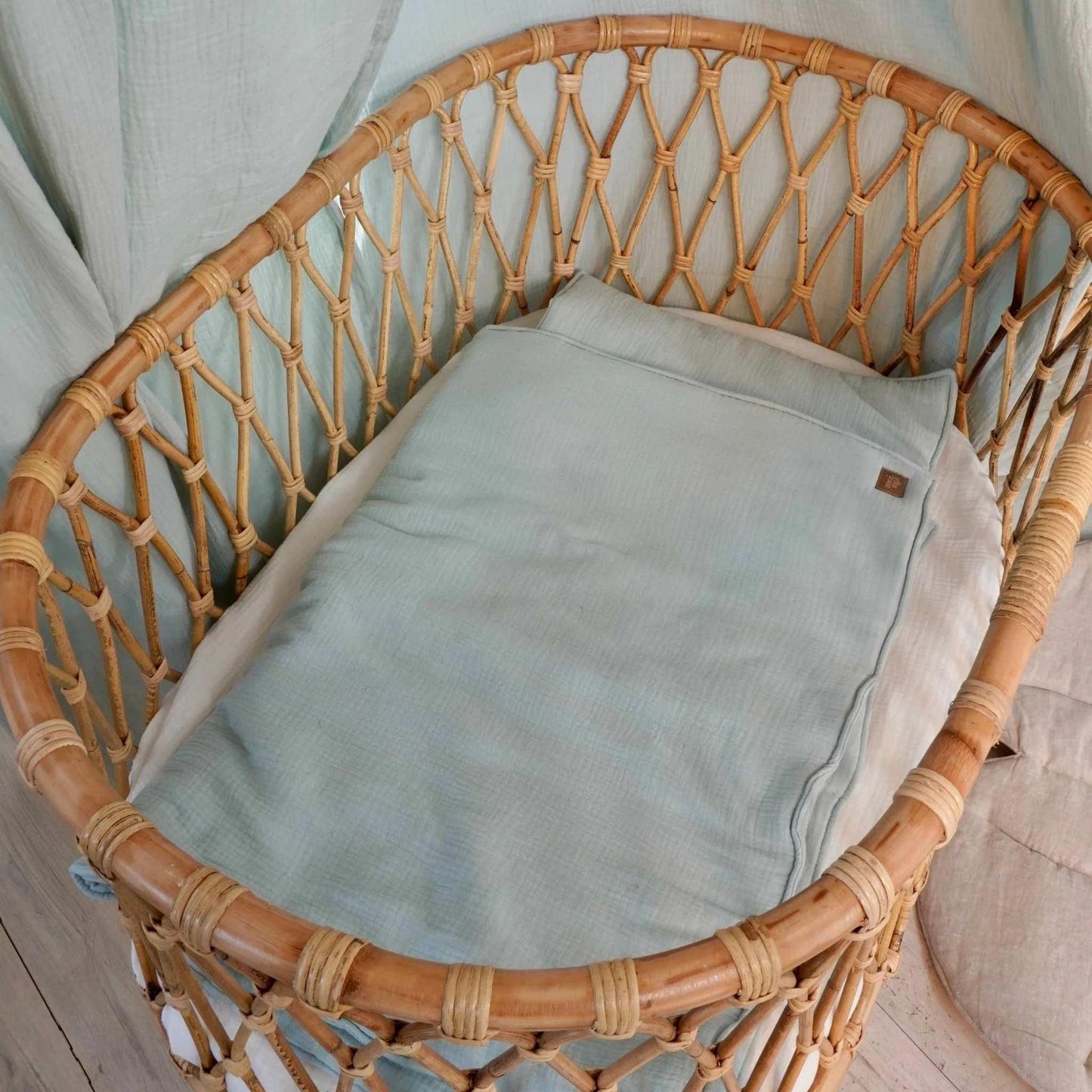 Wicker chair with a light blue cushion against a light-colored wall.