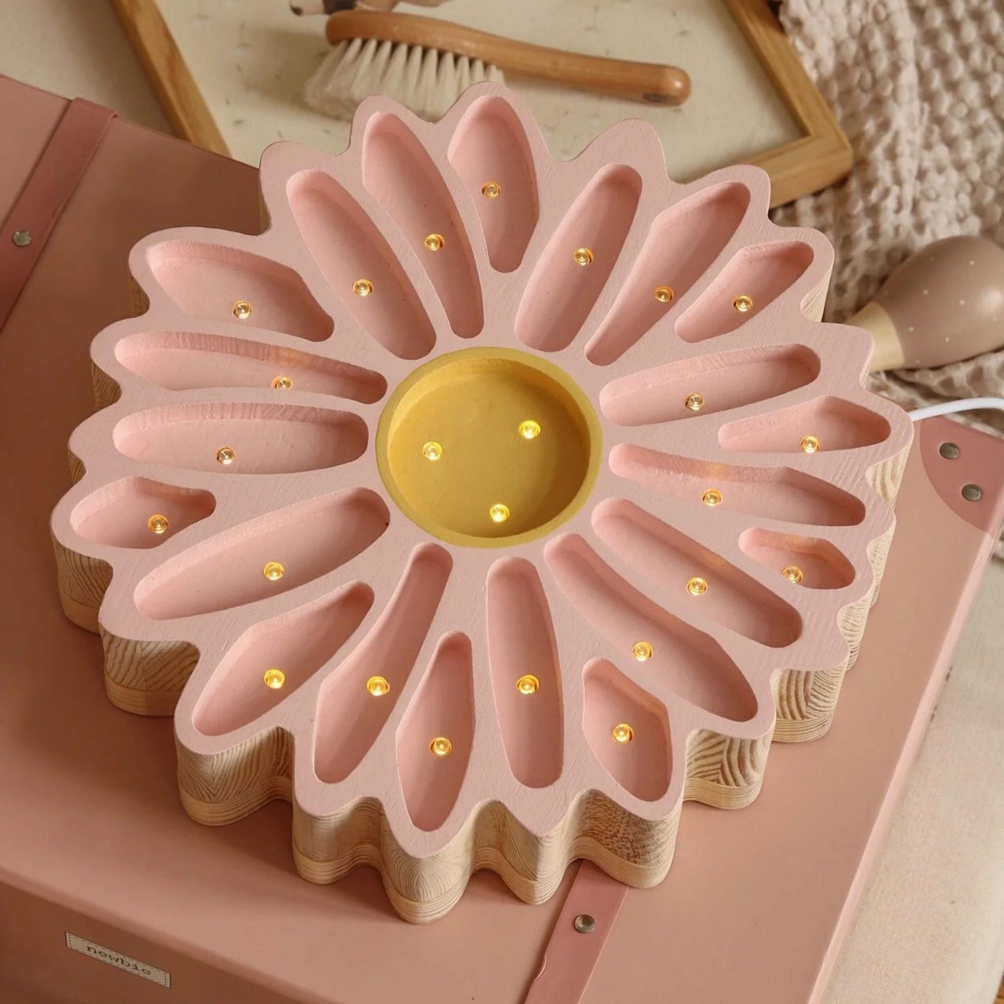 Pink and gold decorative item resembling a flower on a pink surface.