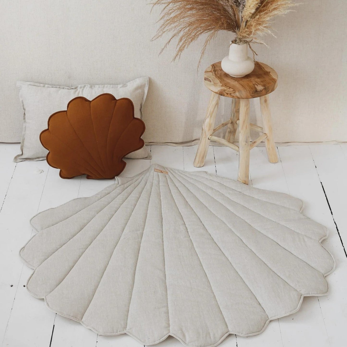 Shell-shaped cushions on a white floor with a wooden stool and decorative elements.