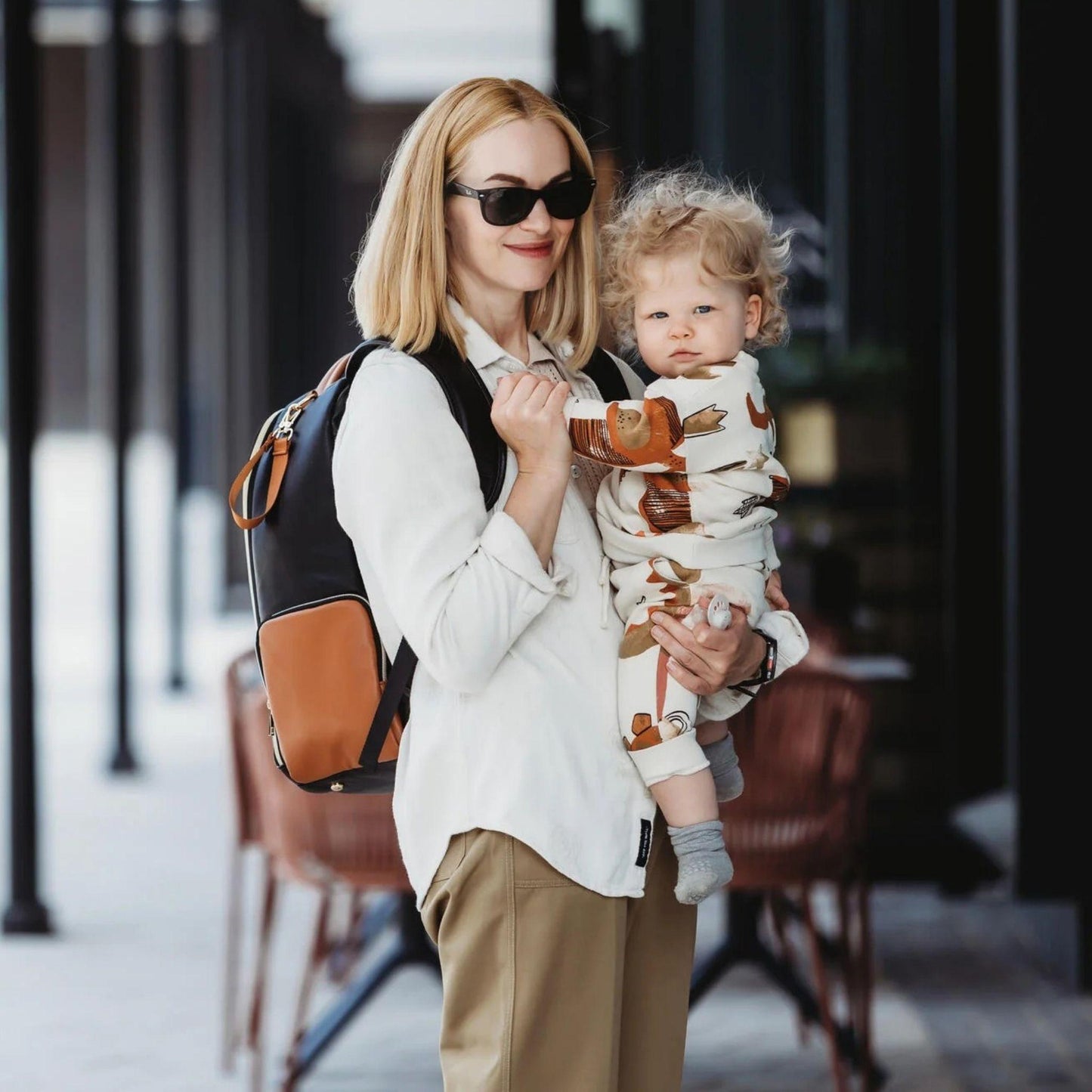 Woman holding a child in a carrier with a blurred background