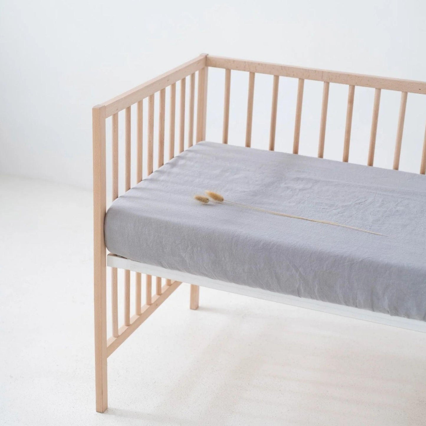 Wooden crib with a gray mattress on a white background