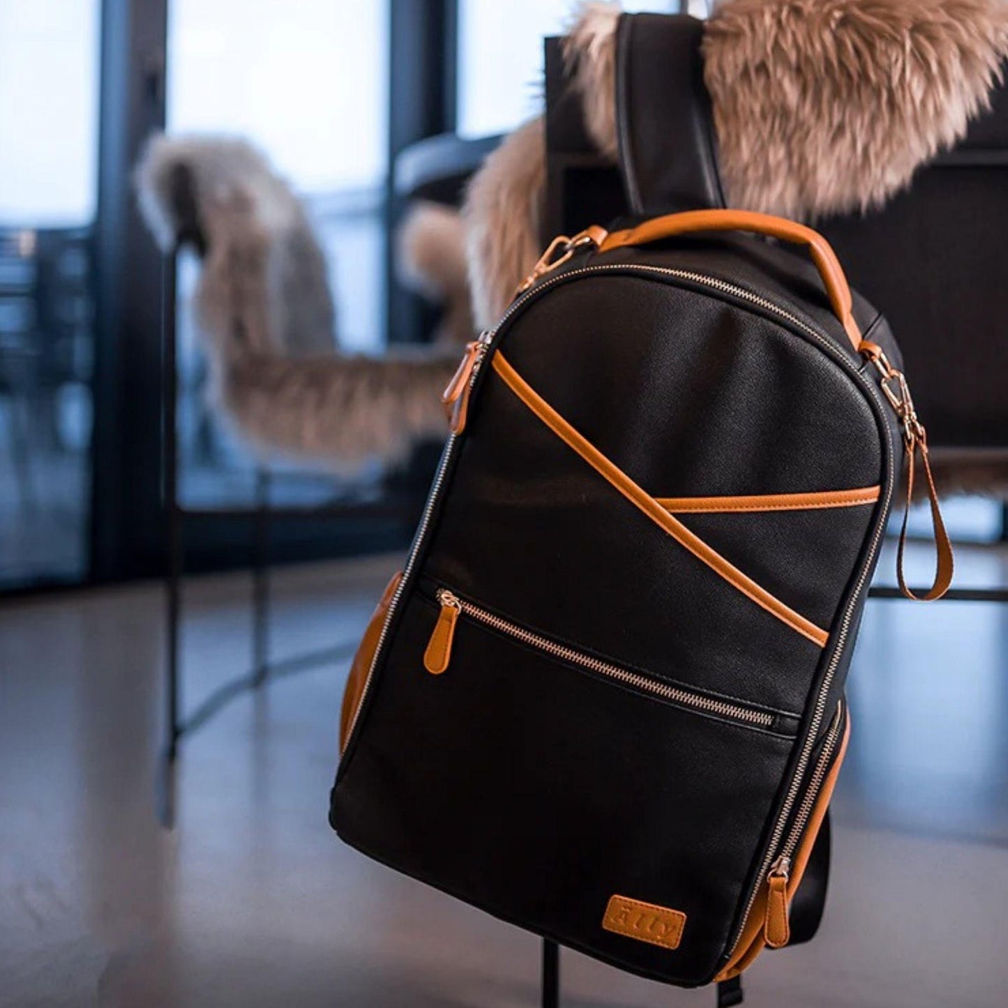 Black diaper bag with brown accents on a stand in an indoor setting