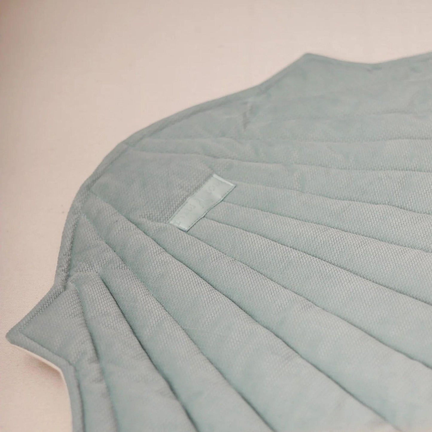 Light blue textured fabric with a small label on a beige background