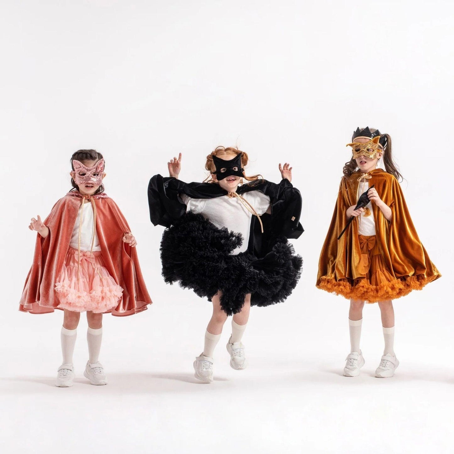 Three children in superhero costumes on a white background