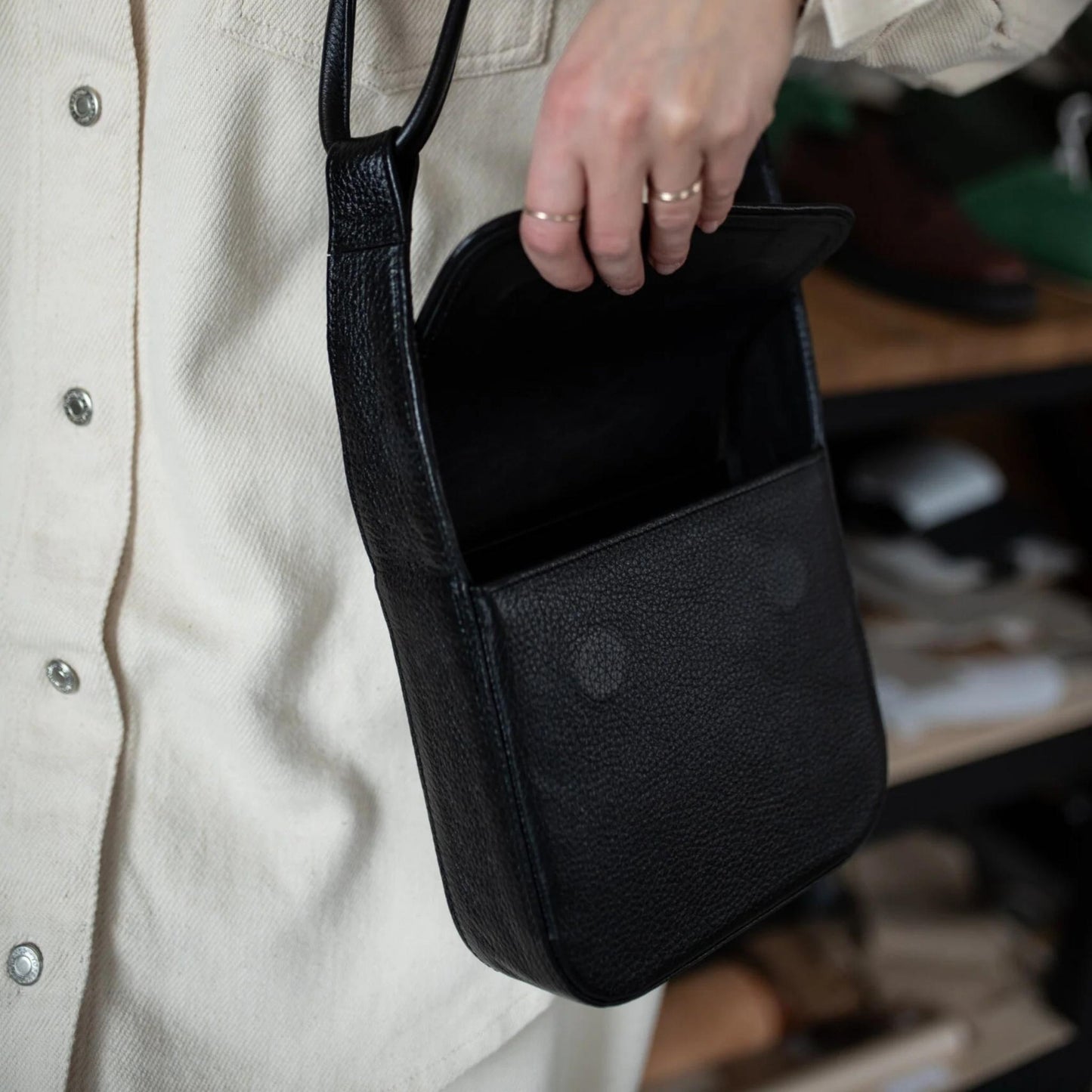 Person holding a black leather bag with a blurred background