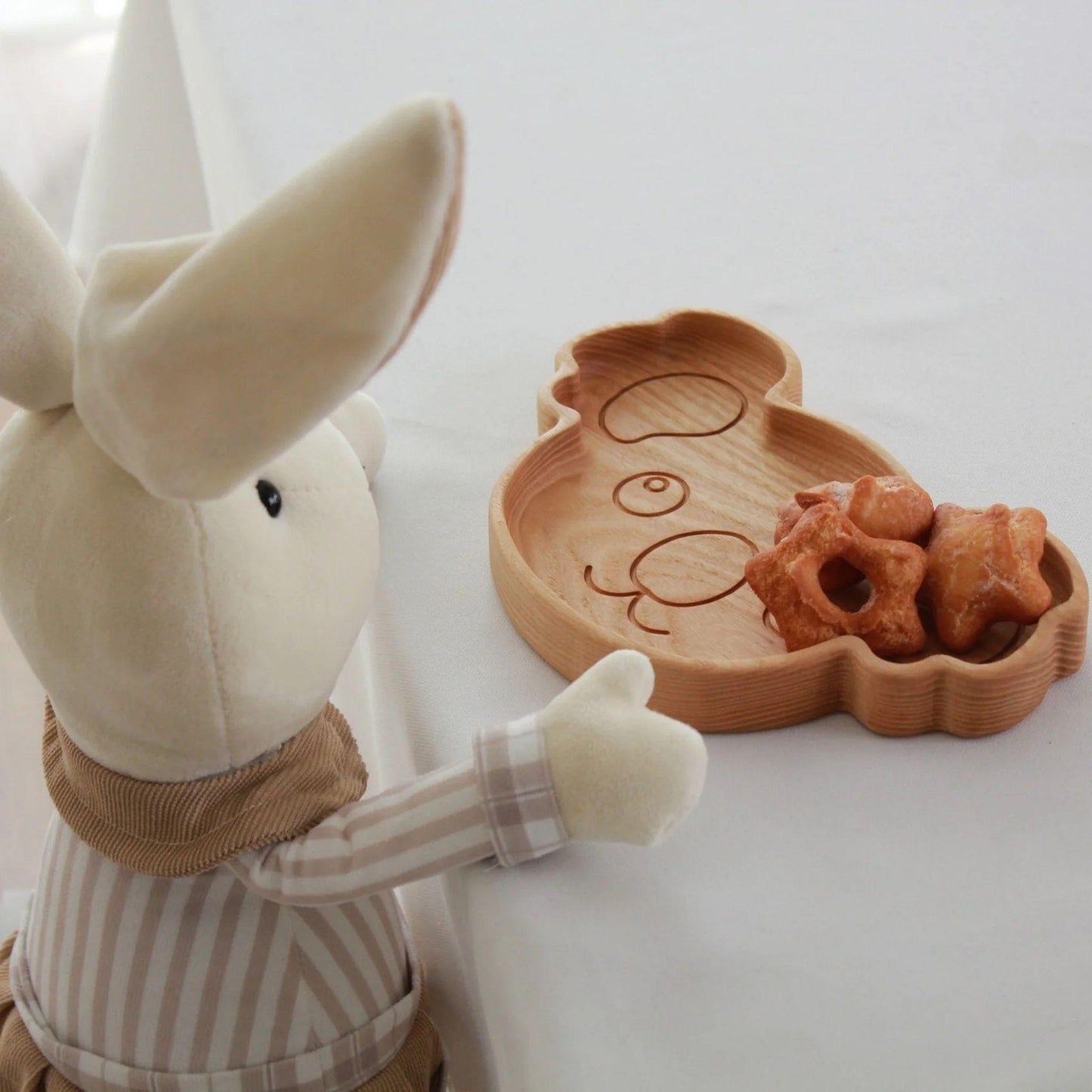 Plush rabbit toy with a wooden tray and cookies on a white background