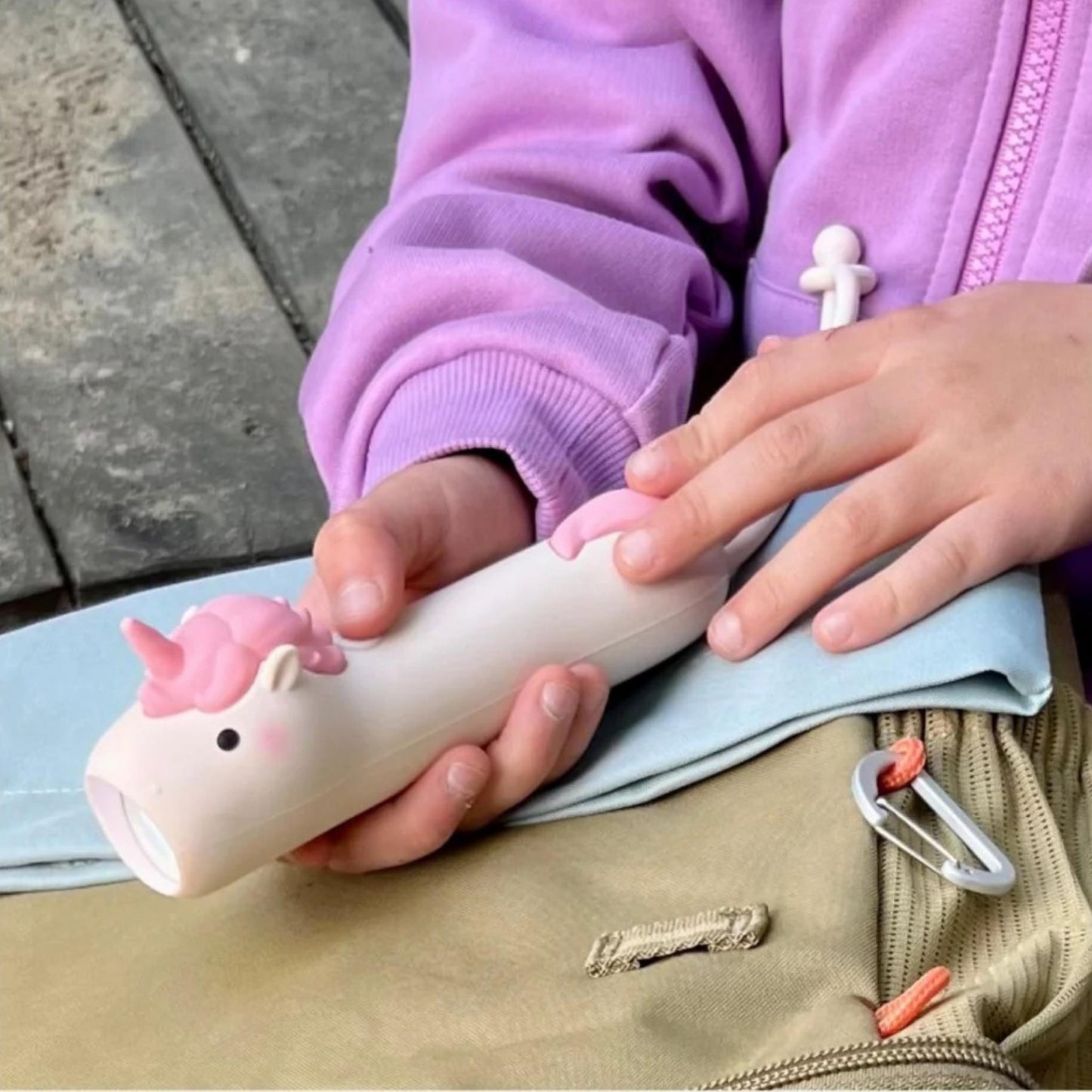 Person holding a unicorn-shaped white device on a concrete surface