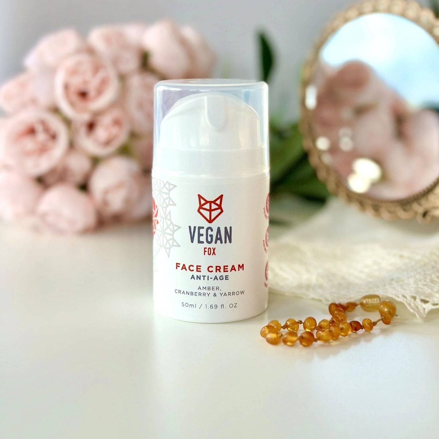 Vegan face cream bottle with flowers and jewelry in the background
