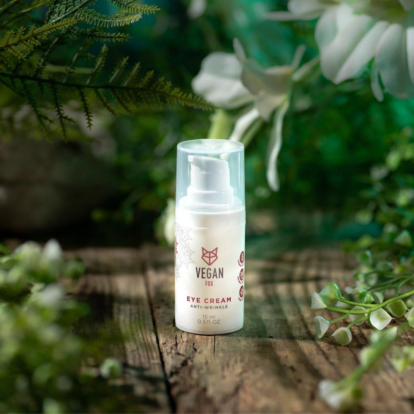 Vegan eye cream bottle on a wooden surface with greenery in the background