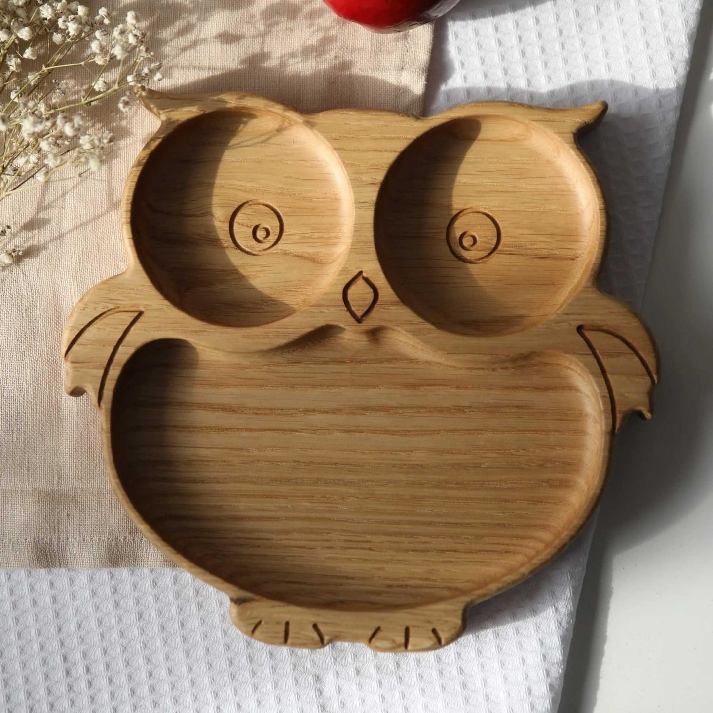 Wooden owl-shaped plate on a white surface with a light background