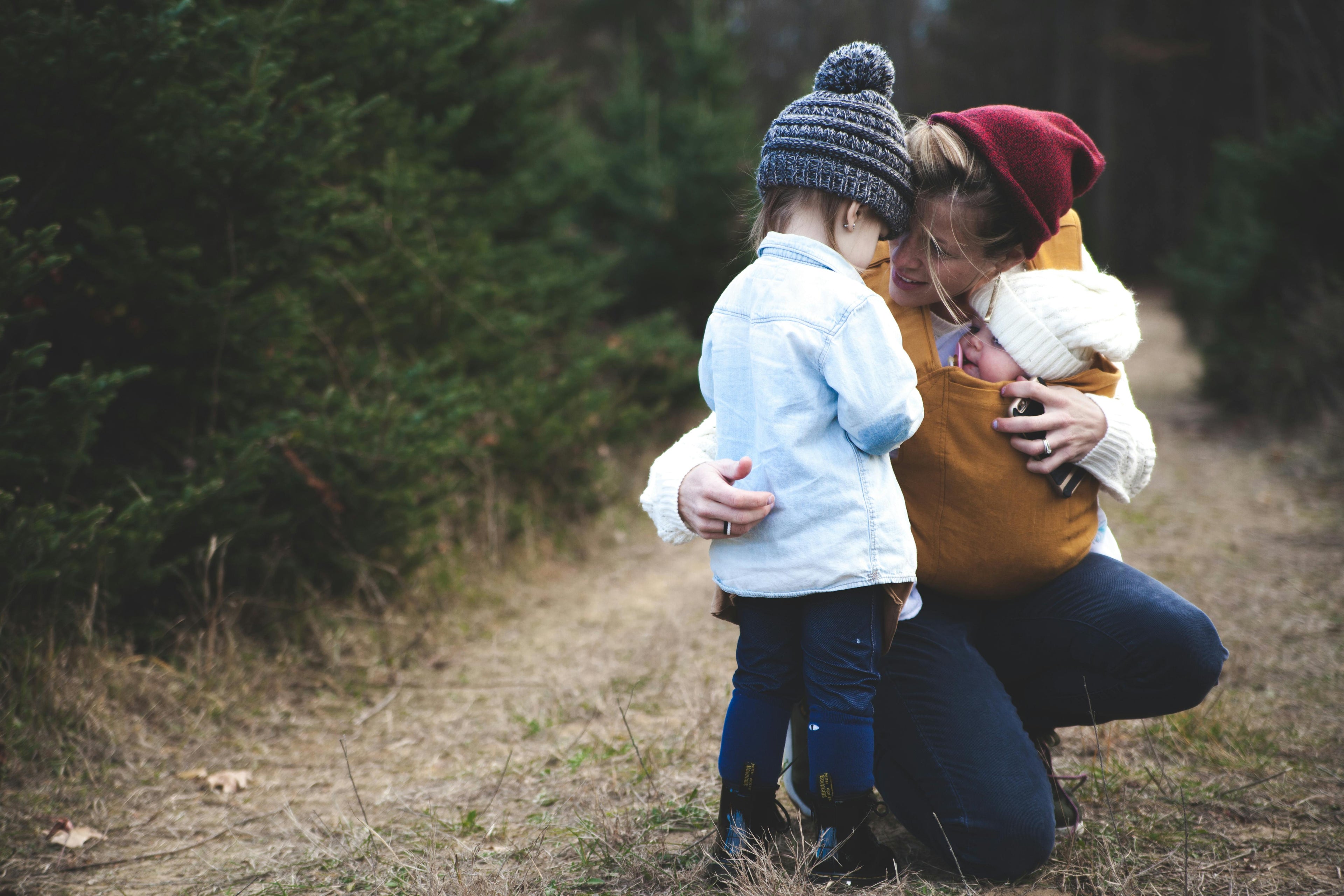 Woman holding a child and a baby in a forest setting