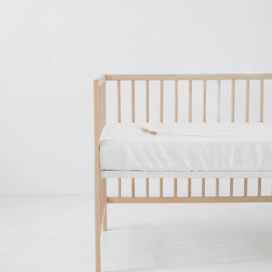 Wooden crib with a white mattress on a white background