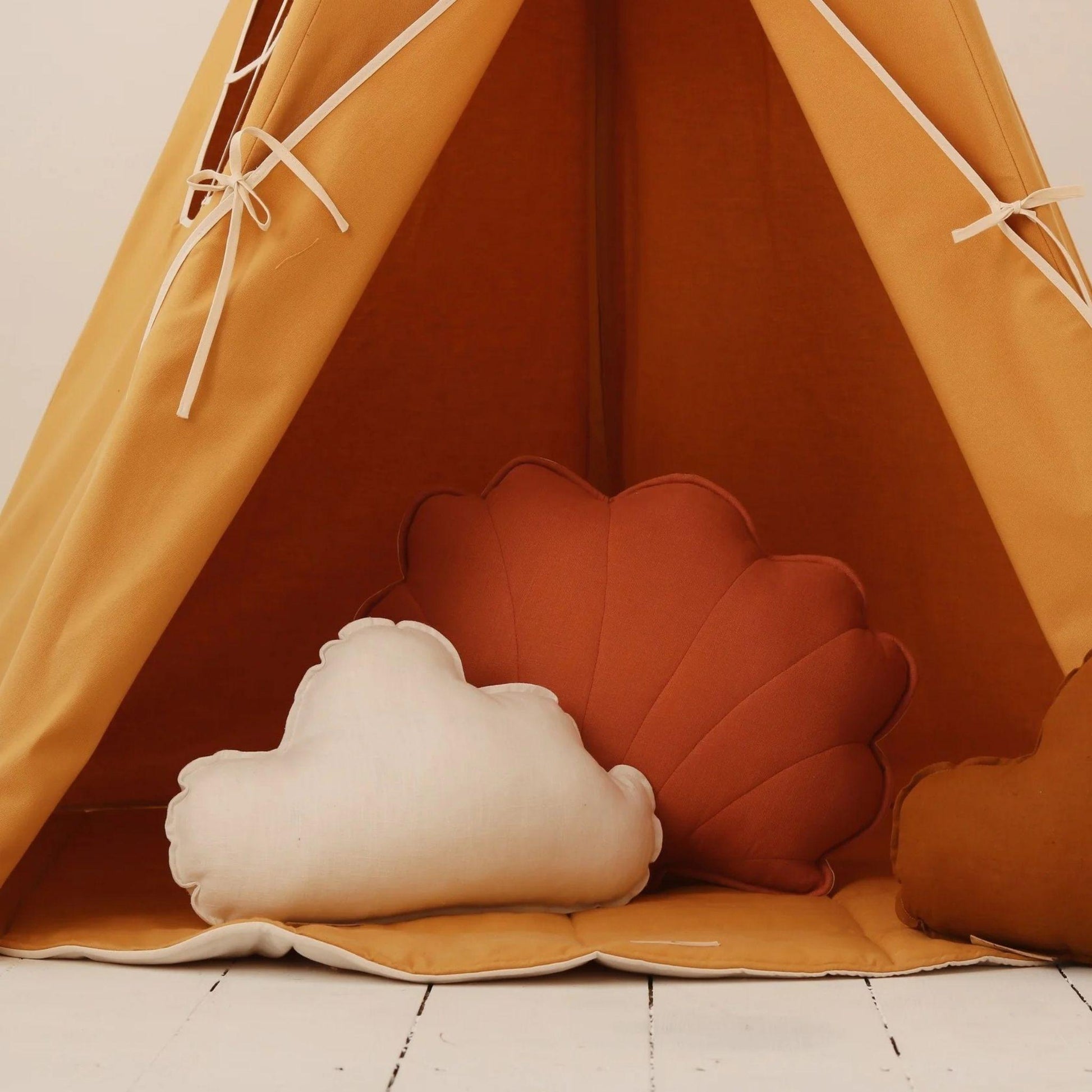 Children's teepee with cloud and shell-shaped cushions on a wooden floor.