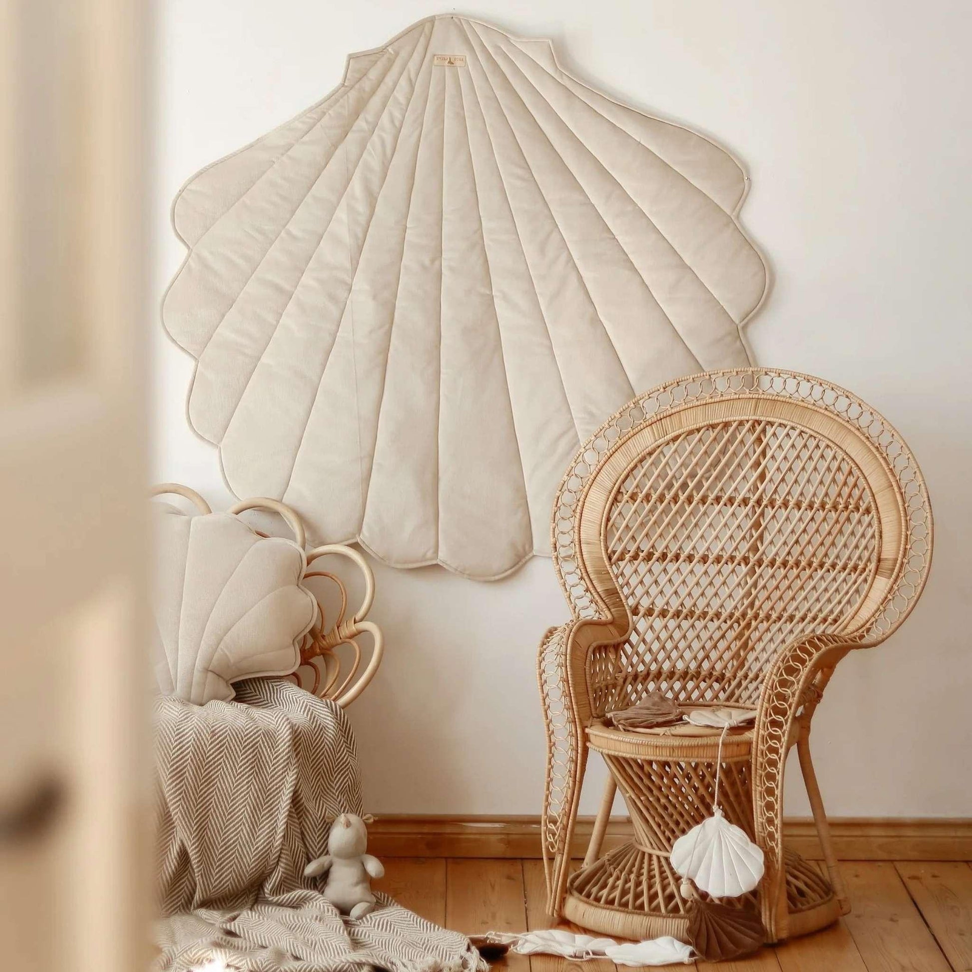 Wicker chair and shell-shaped wall art in a room with wooden floor.