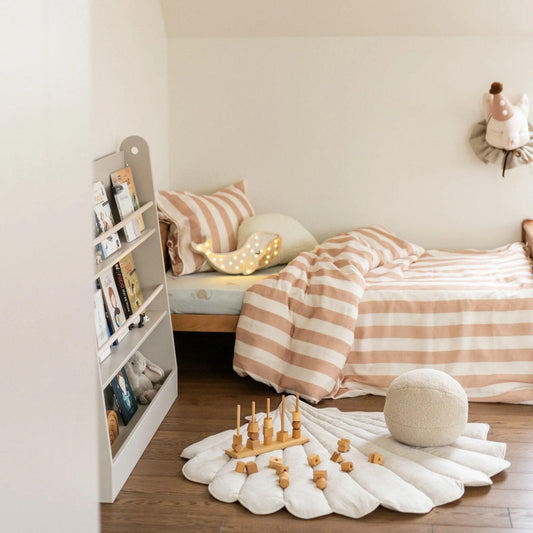Children's bedroom with striped bedding, toys, and a bookshelf.