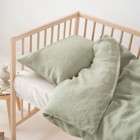 Light green bedding on a wooden bed frame against a white wall.