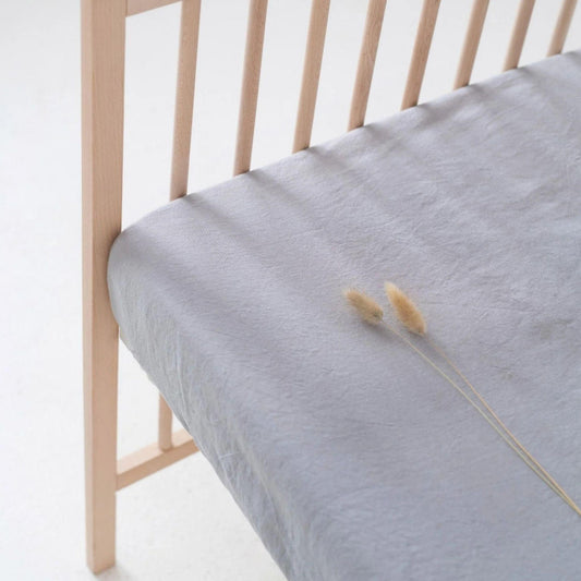 Light blue mattress cover on a wooden bed frame with a white background