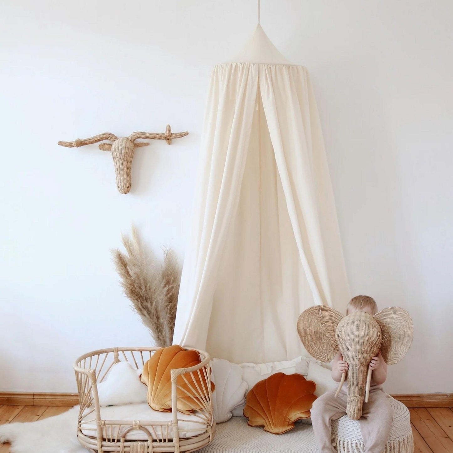Child wearing elephant headband in a cozy room with a canopy and decorative items.