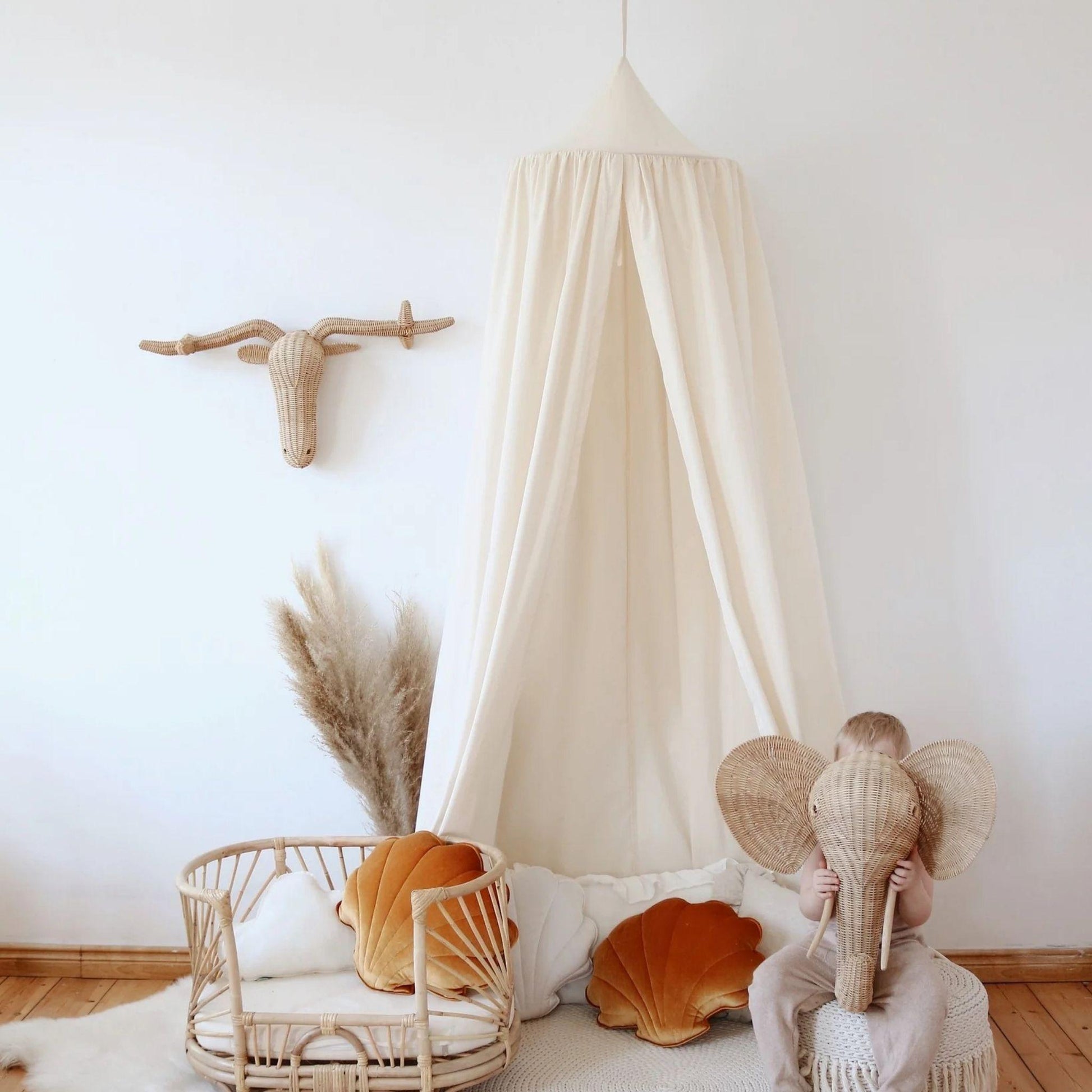 Child wearing elephant headband in a cozy room with a canopy and decorative items.