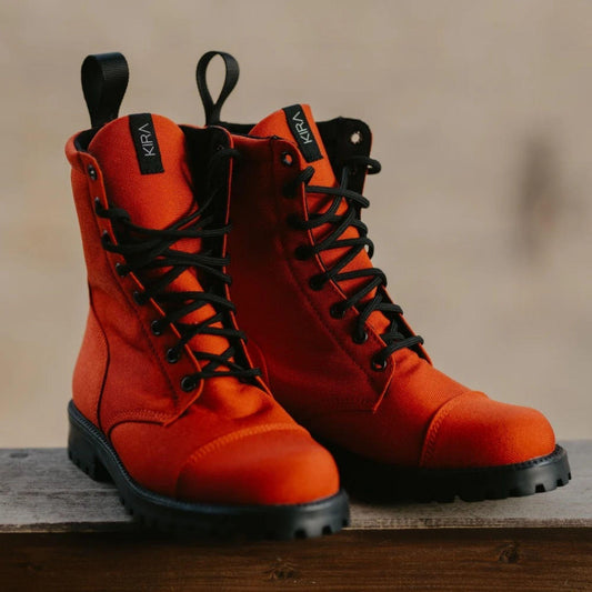 Pair of orange boots with black laces on a wooden surface