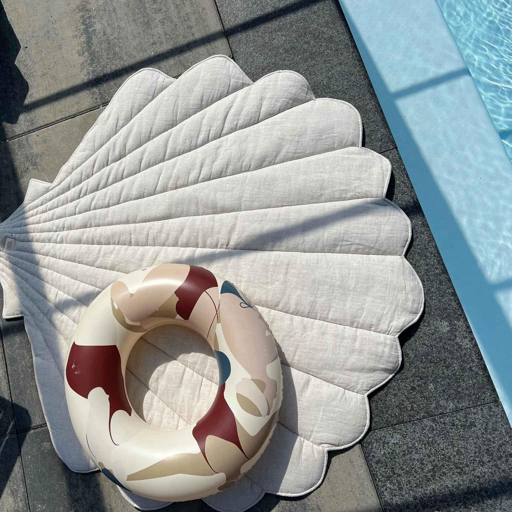 Inflatable ring with cartoon design on a white quilted mat by a pool