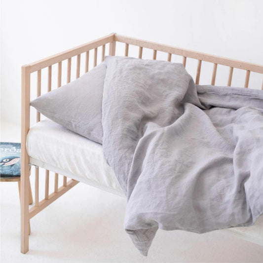 Beige crib with gray bedding on a white background