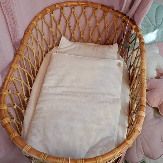 Wicker chair with a beige cushion on a pink background