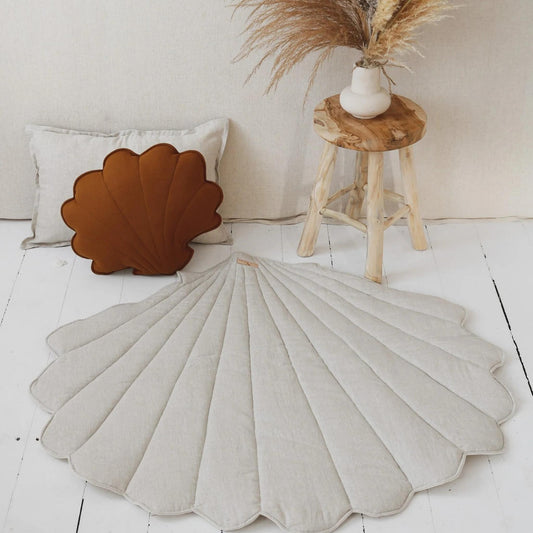 Shell-shaped cushions on a white floor with a wooden stool and decorative elements.