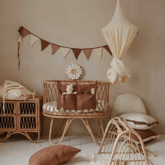 Nursery room with wicker crib, decorative pillows, and hanging lamp.