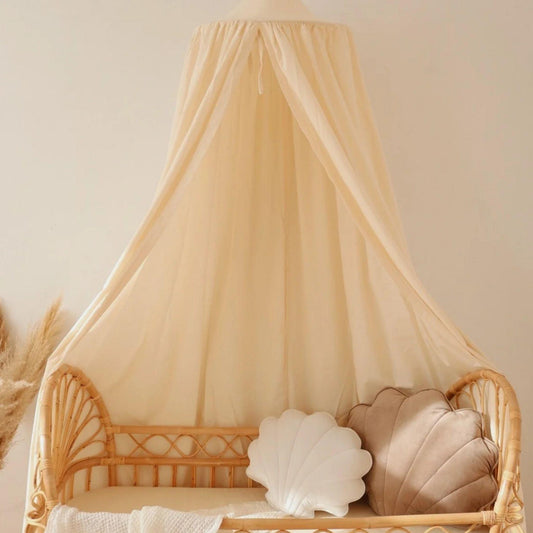 Wicker chair with a beige canopy and shell-shaped cushions on a neutral background