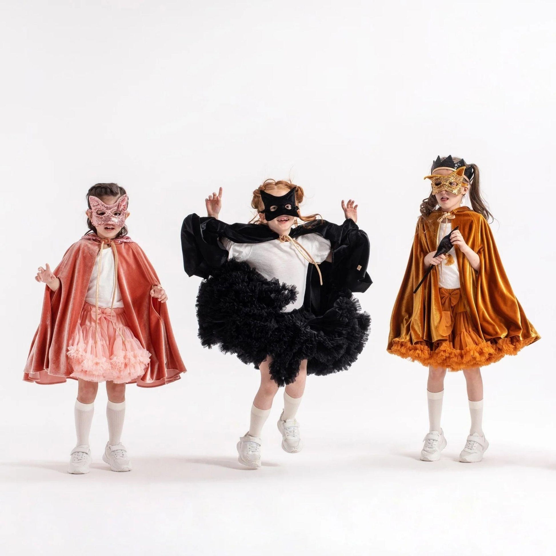 Three children in superhero costumes on a white background